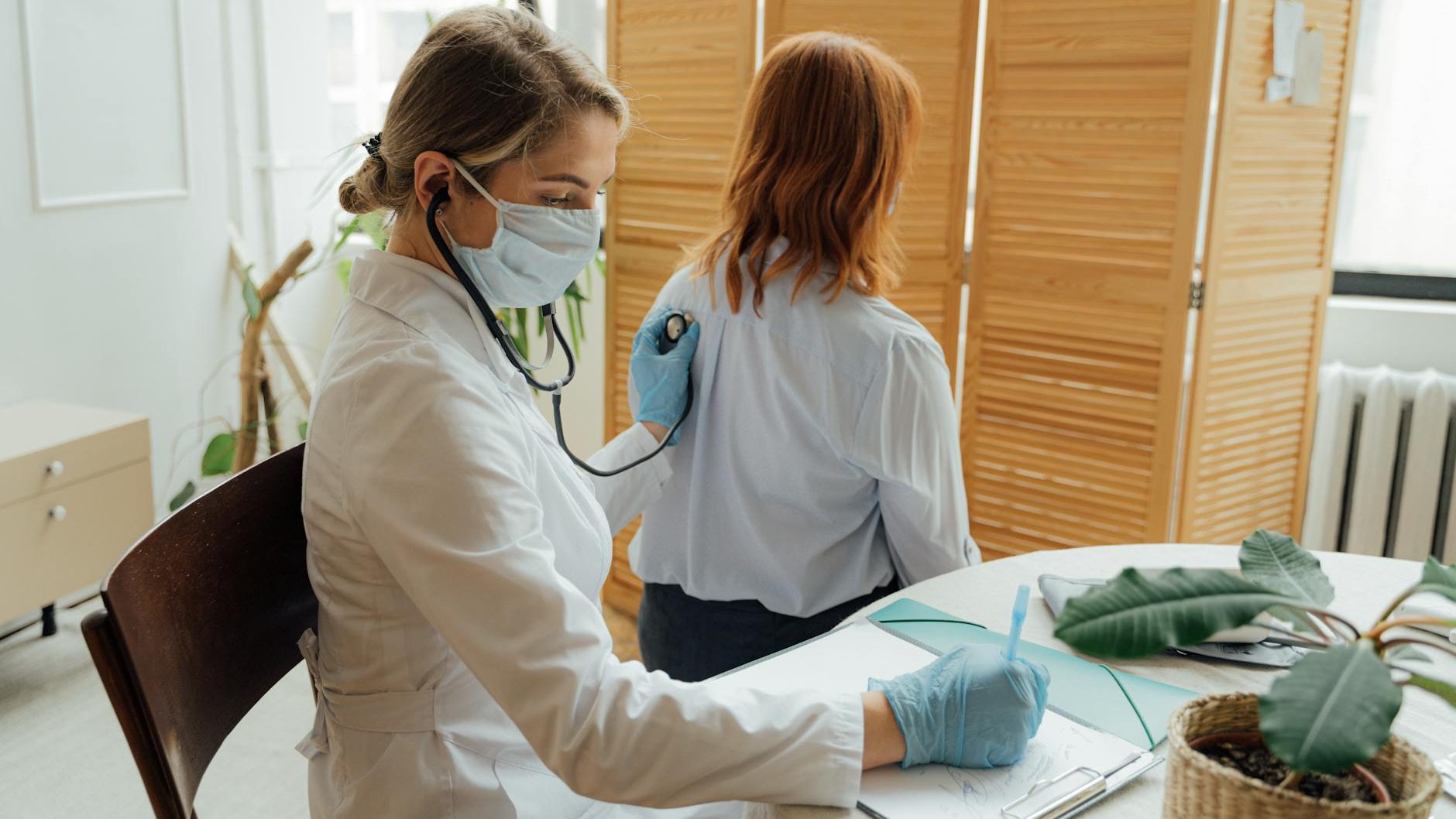 A family doctor listens to a patient's heartbeat and breathing with a stethoscope. 