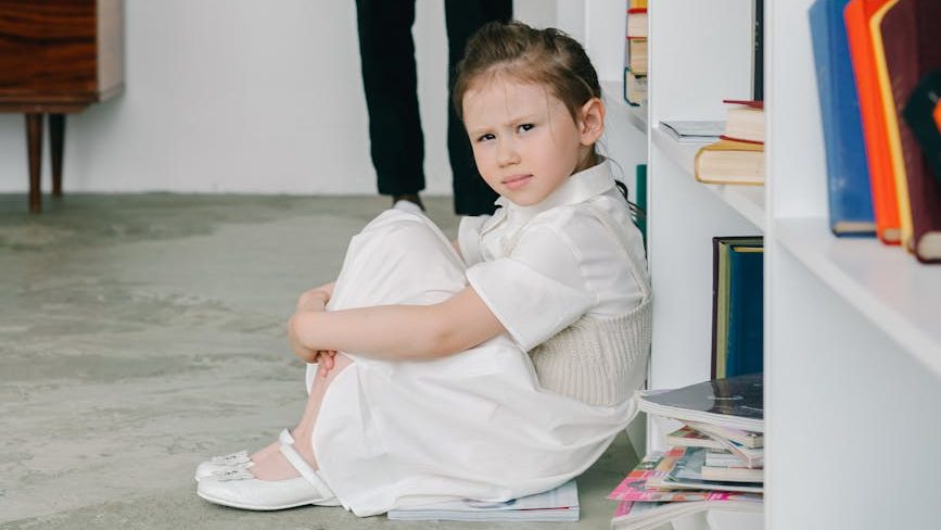 A frustrated child sitting in front of a row of cubbies.